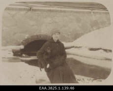 Naine koeraga jõe ääres istumas. 1917