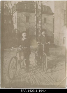 Poiss ja tüdruk jalgratastega linnamaja hoovis. 1880-ndad - 1900-ndad