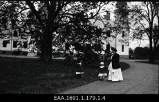 Naine kahe lapsega Alatskivi mõisa peahoone taustal (1890-ndad - 1910-ndad)