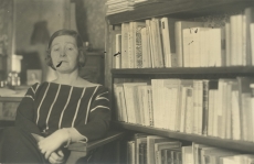 Marie Under istumas oma raamaturiiuli juures